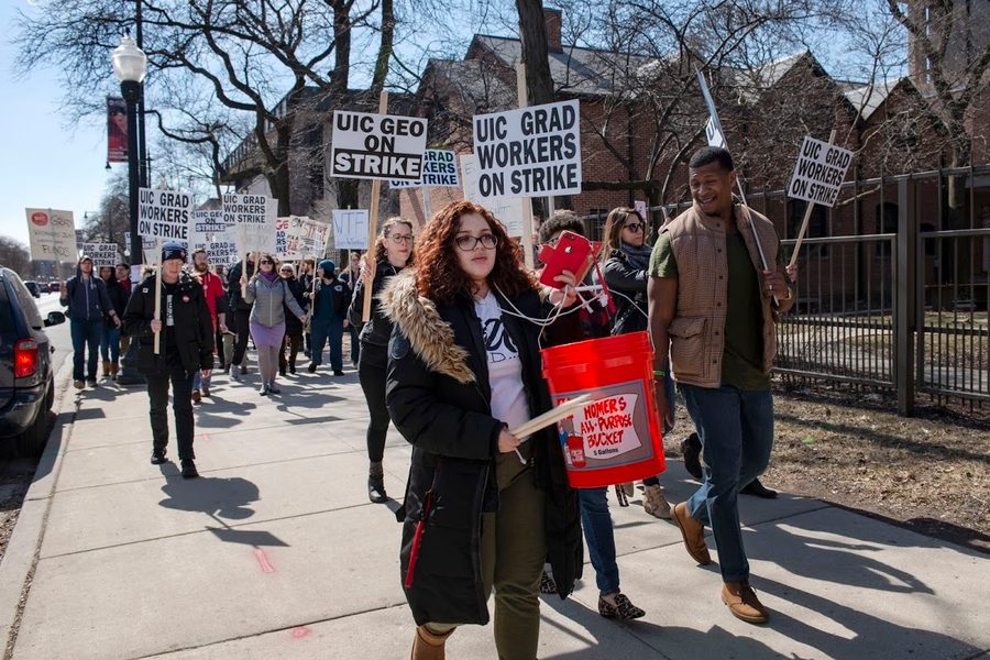 A graduate worker beating a drum leads a picket line in the 2019 GEO strike.